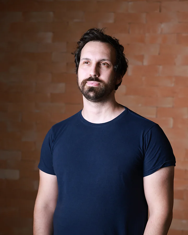 Felipe Fiori, psychoanalyst, in front of a brick wall, looking up.